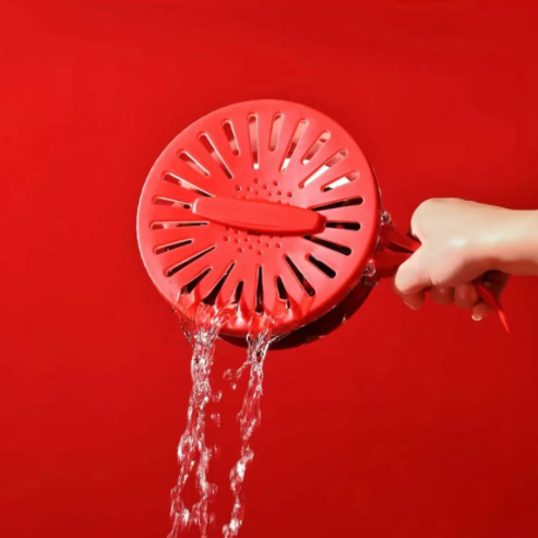 Red shower head with water flowing against a red background