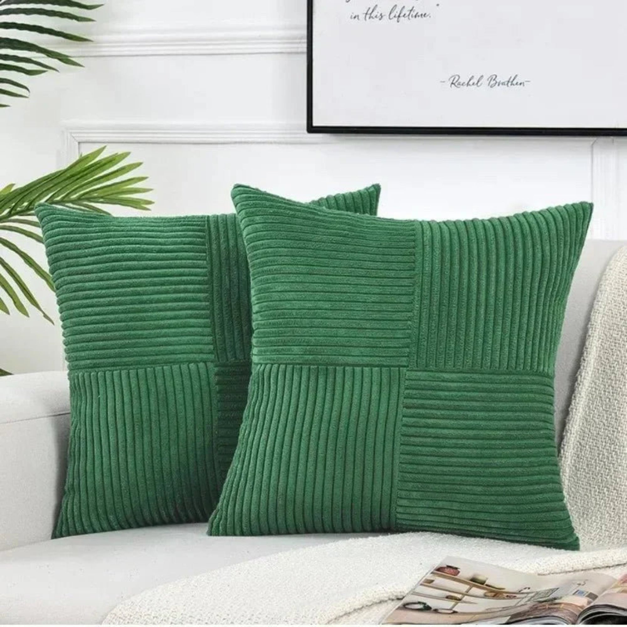 Two green ribbed throw pillows on a white couch with a framed picture in the background.