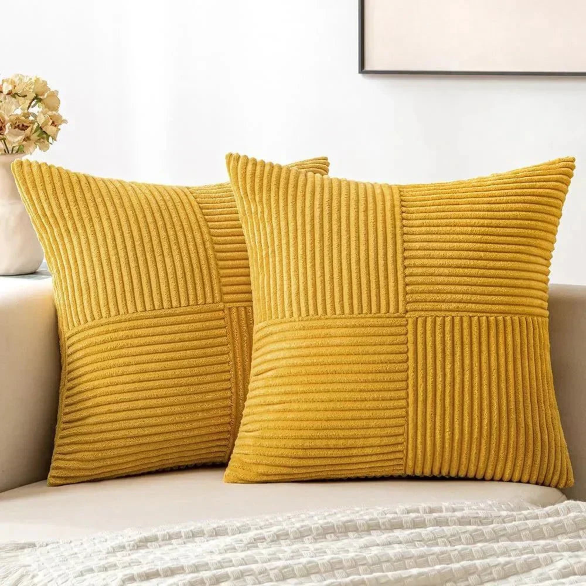 Two mustard yellow textured pillows on a sofa with a neutral background