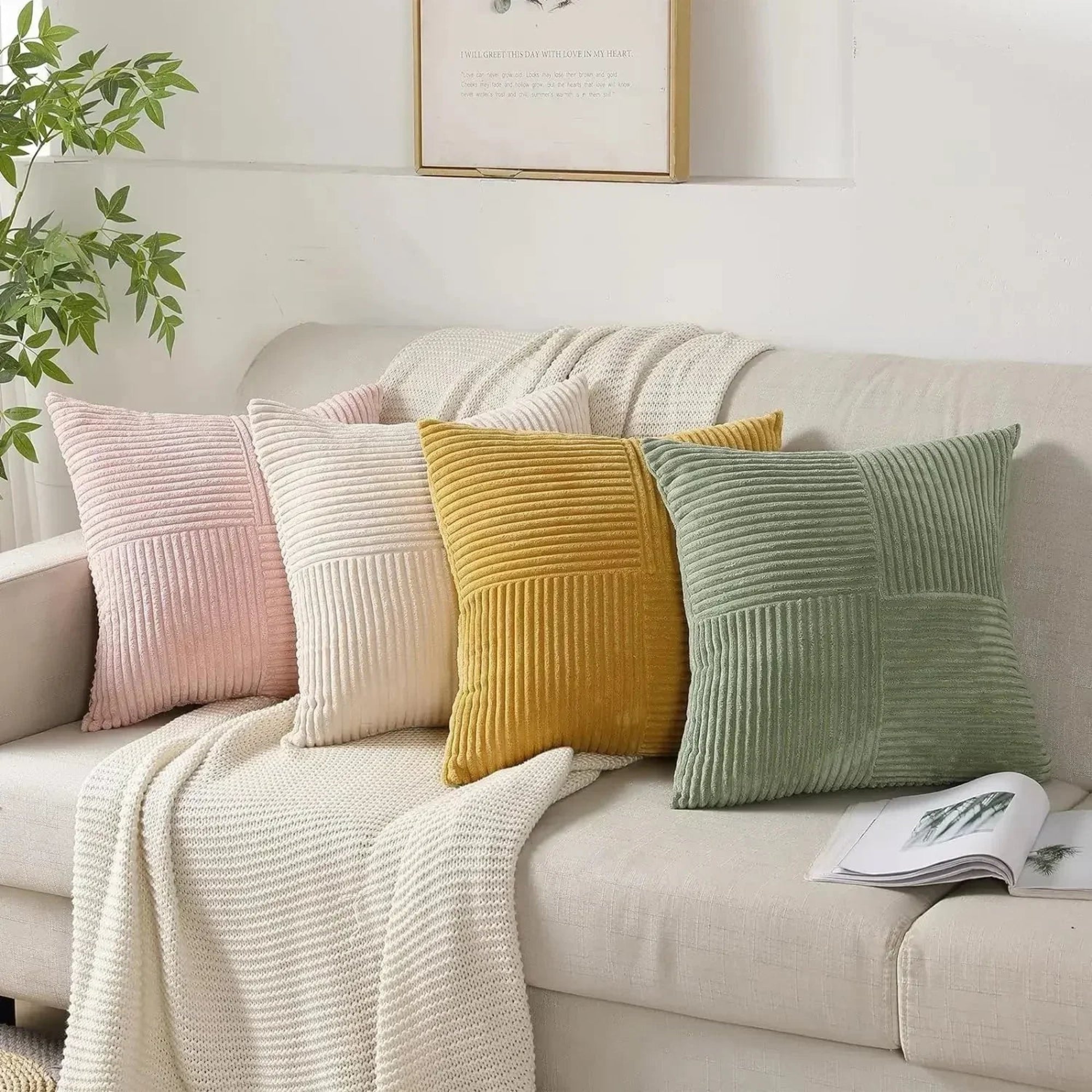 Colorful pillows on a beige sofa with a plant and framed picture in the background