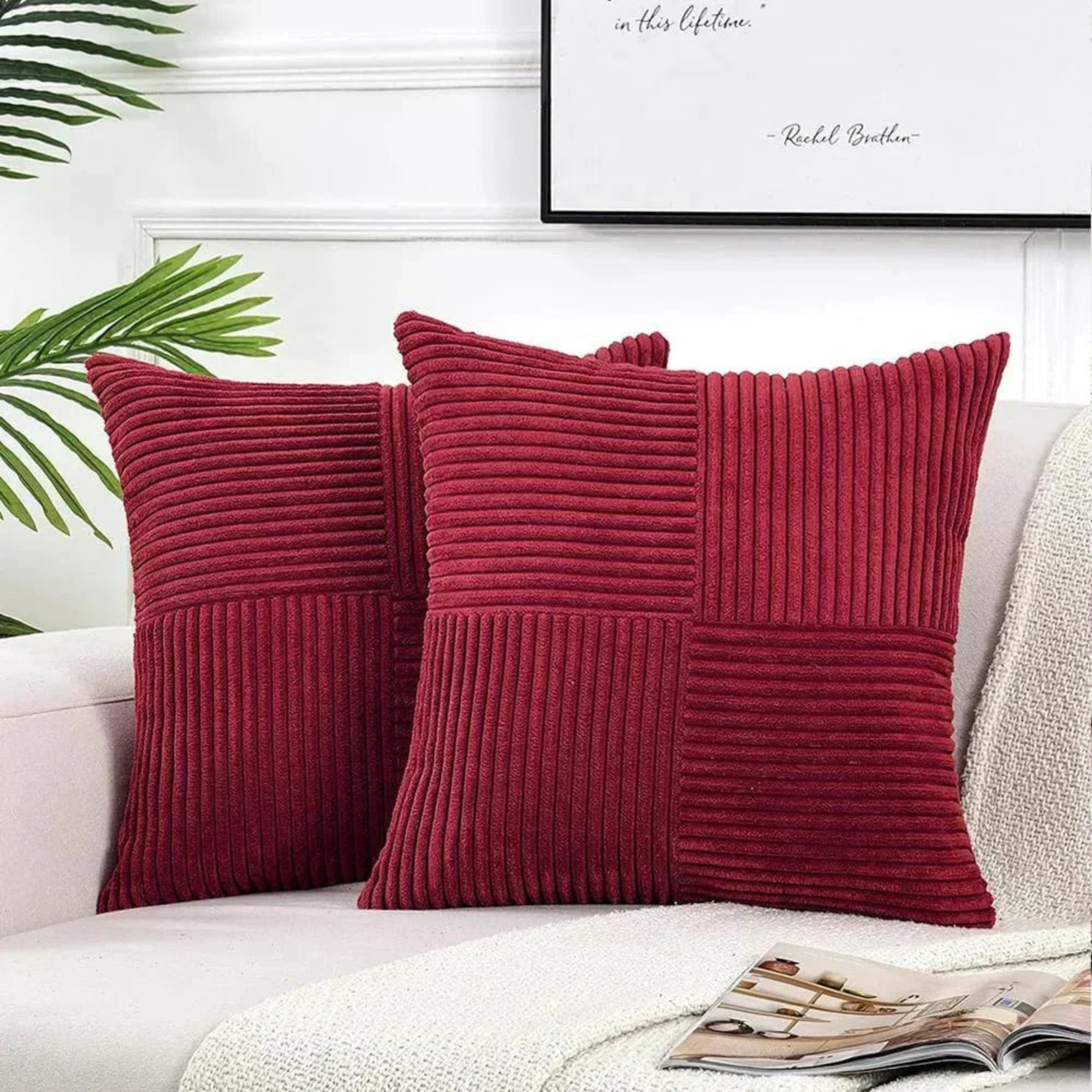 Two red textured pillows on a white couch with a framed quote in the background.