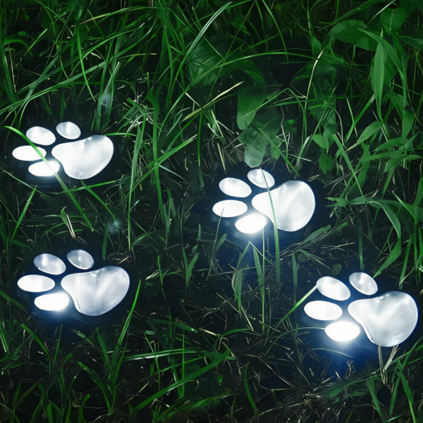 Solar-powered paw print lights glowing in the dark on grass