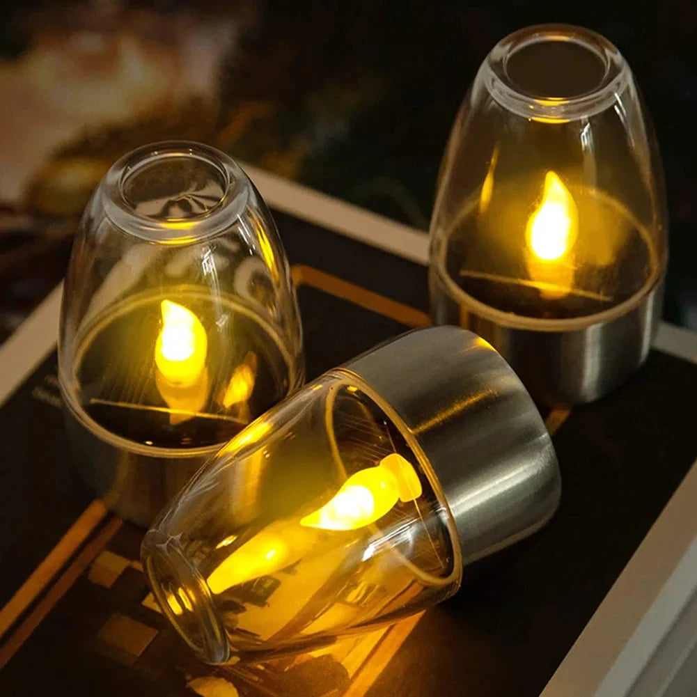 Three glass candle holders on a reflective surface.
