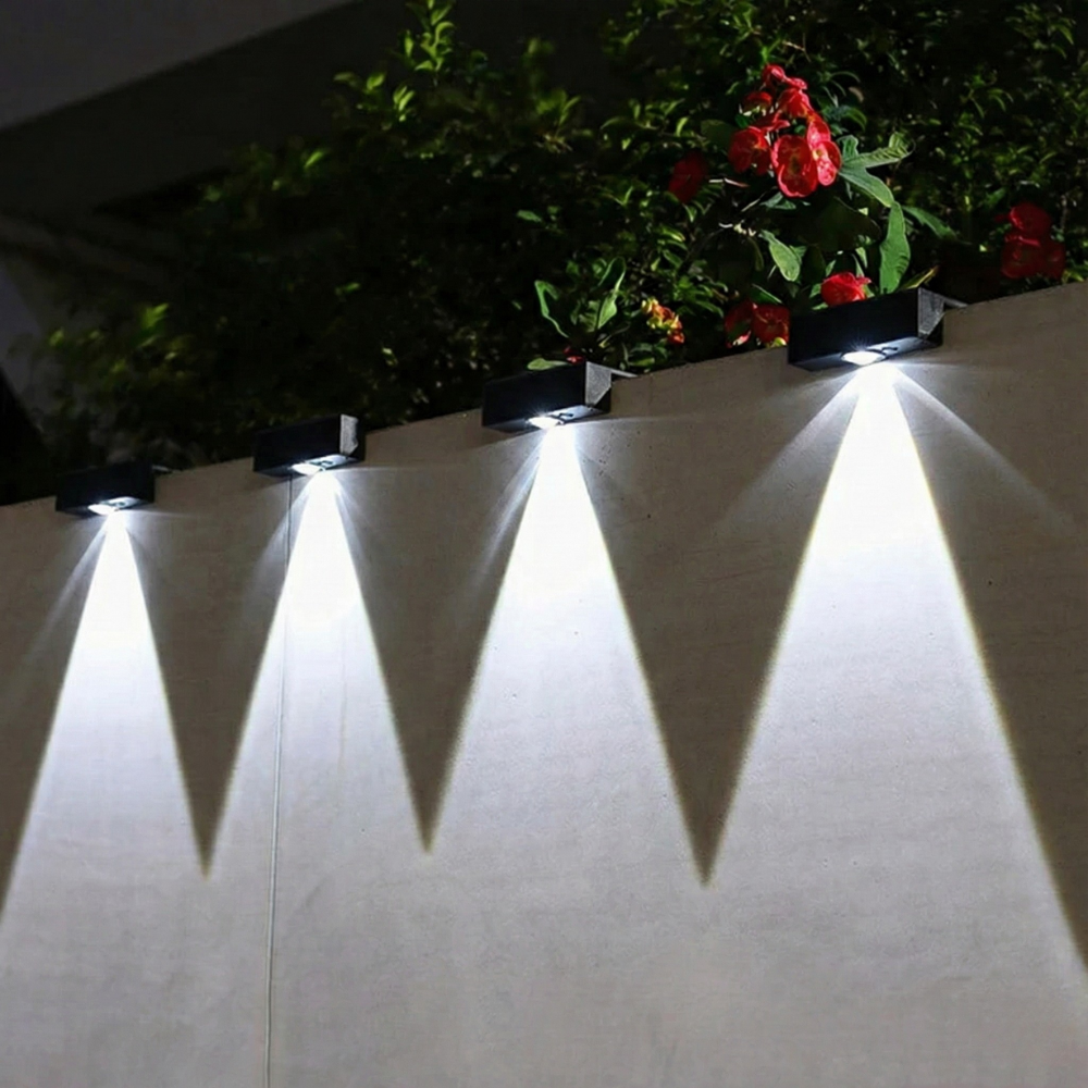 Solar-powered outdoor lights on a wall with plants in the background