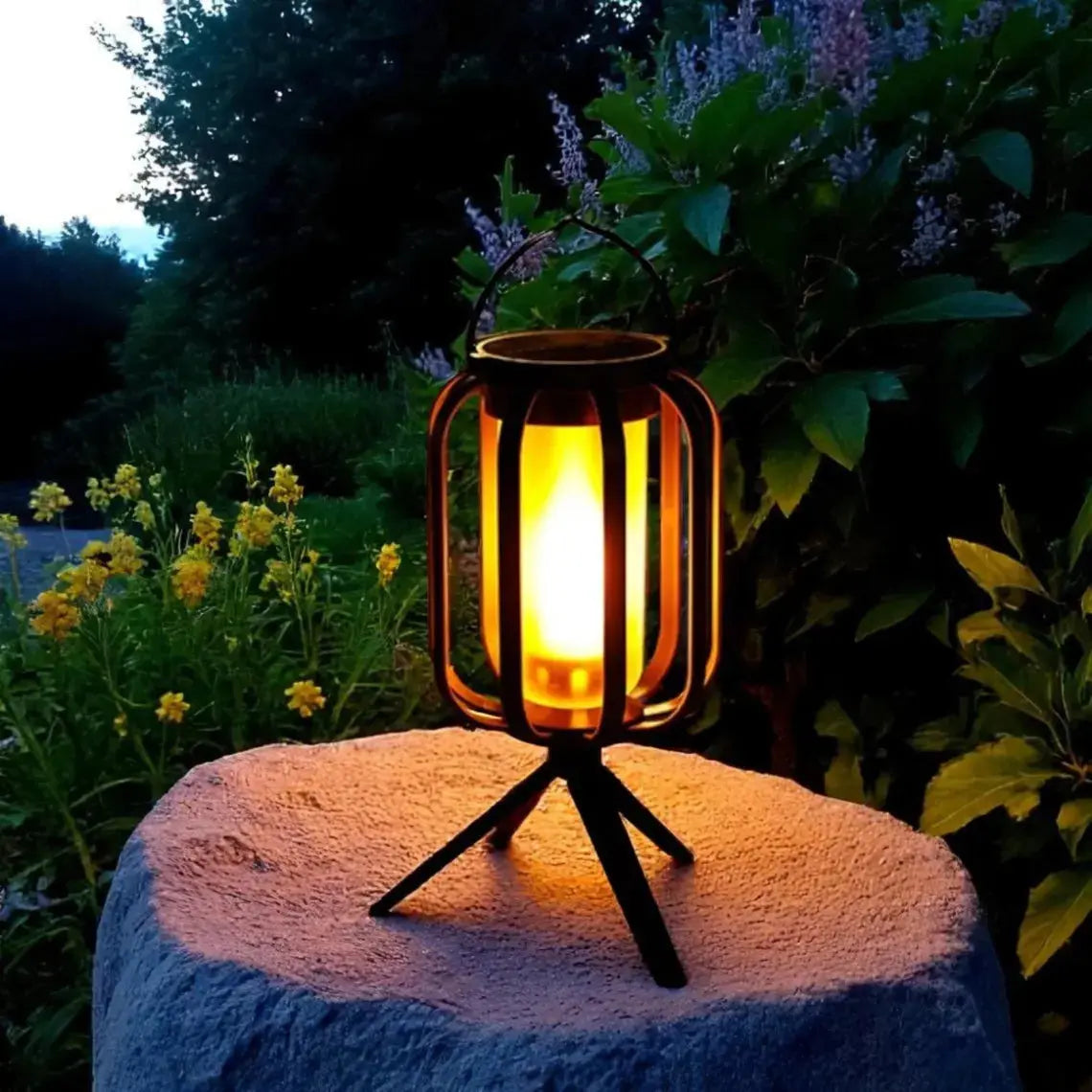 Decorative outdoor lantern with glowing light on a stone surface surrounded by plants and flowers.
