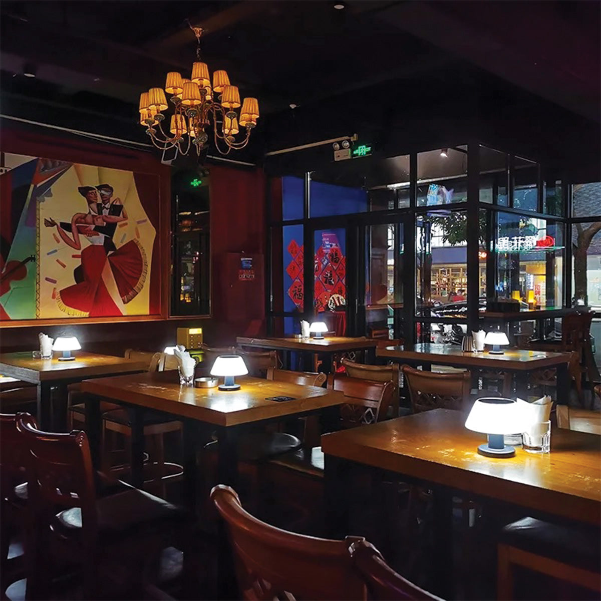 Dining area with tables, chairs, and a chandelier in a restaurant.