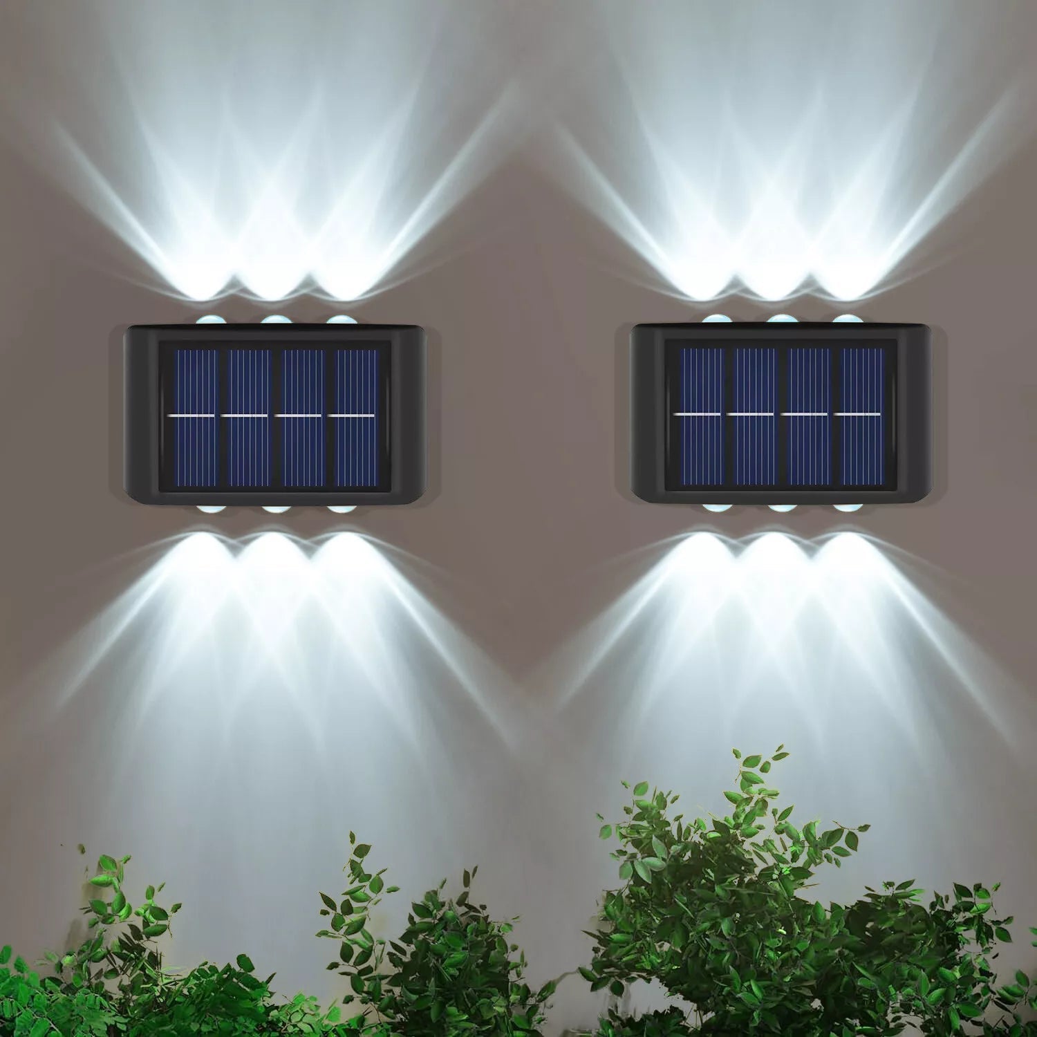 Two solar-powered wall lights on a white wall with greenery at the bottom.