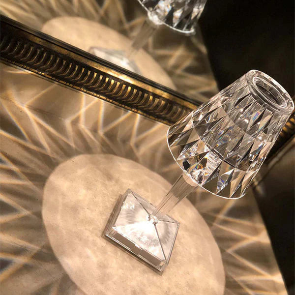 Close-up of a crystal candle holder on a textured surface with a mirror reflection.