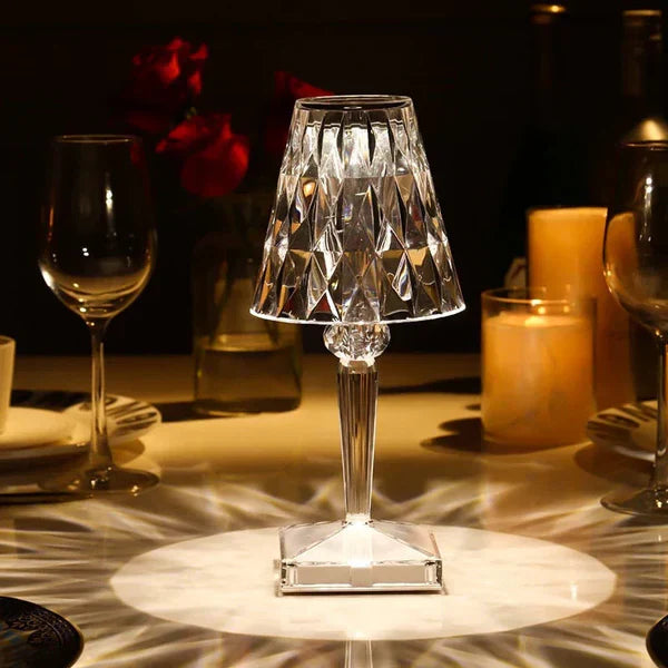 Decorative crystal table lamp on a table with wine glasses and candles in the background