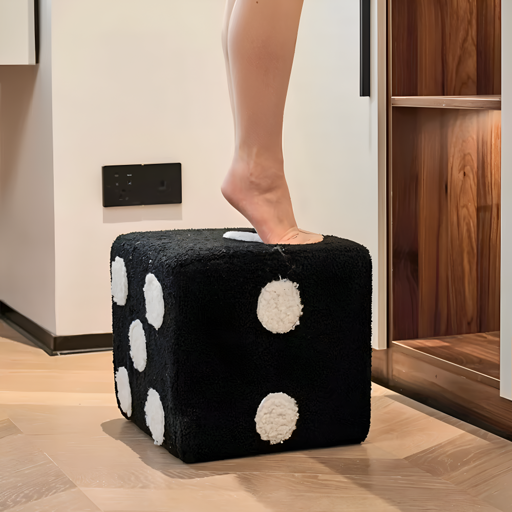 Black cube-shaped ottoman with white polka dots being used as a footstool.