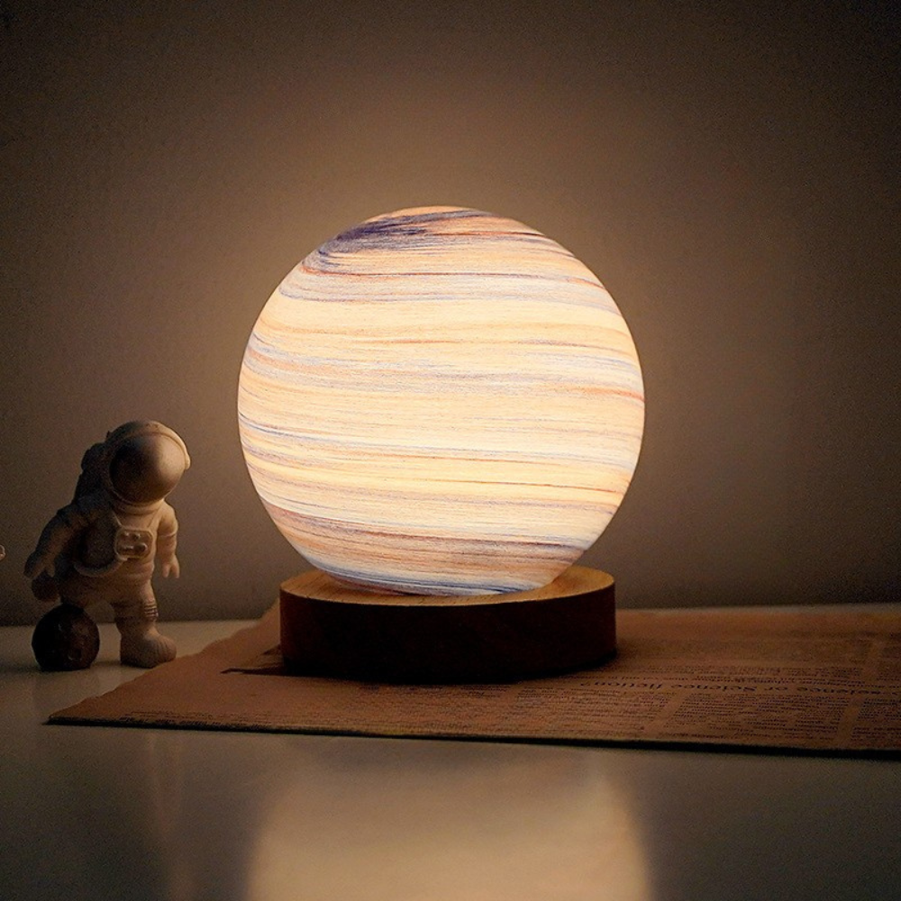 Spherical lamp with wooden texture on a stand, resembling a planet, next to an astronaut figurine on a dark background.