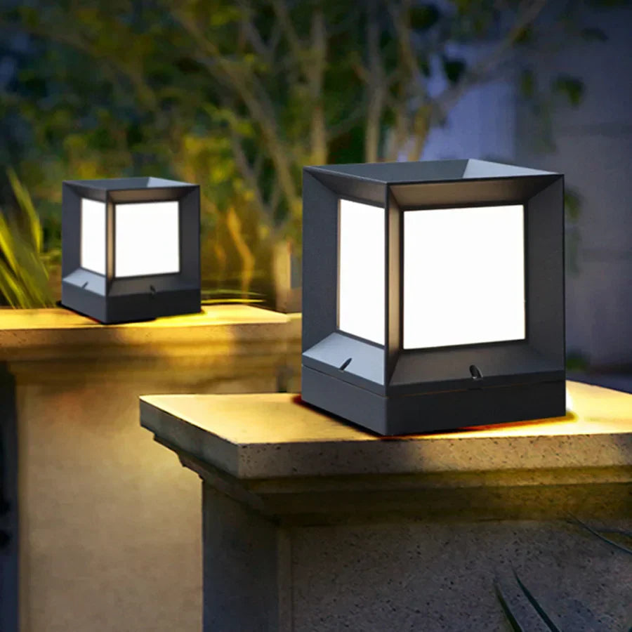 Two square outdoor lights on a stone surface with a blurred natural background