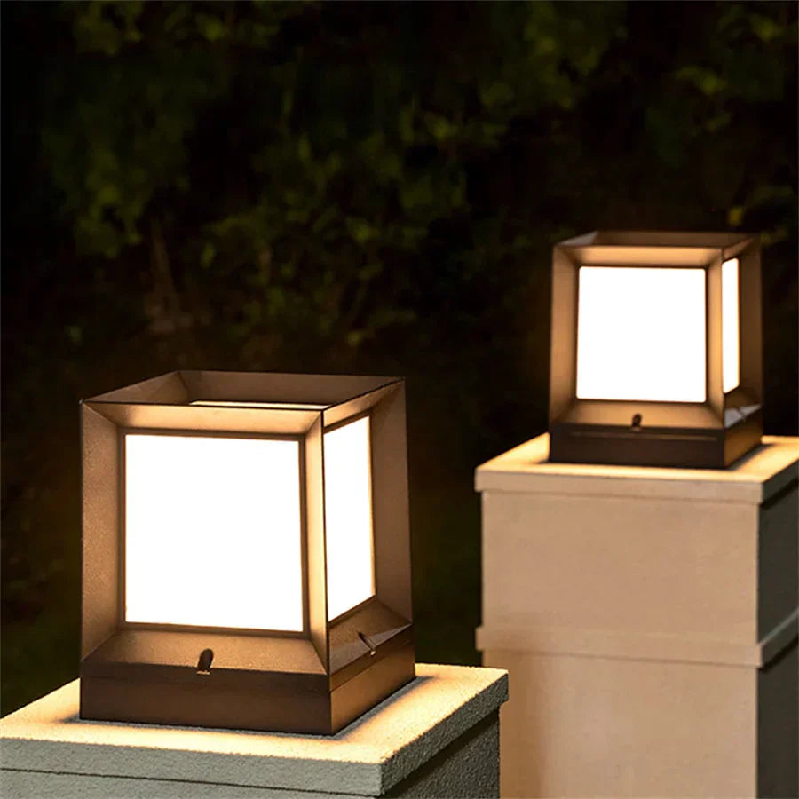 Two square outdoor lights on concrete pillars with a dark background