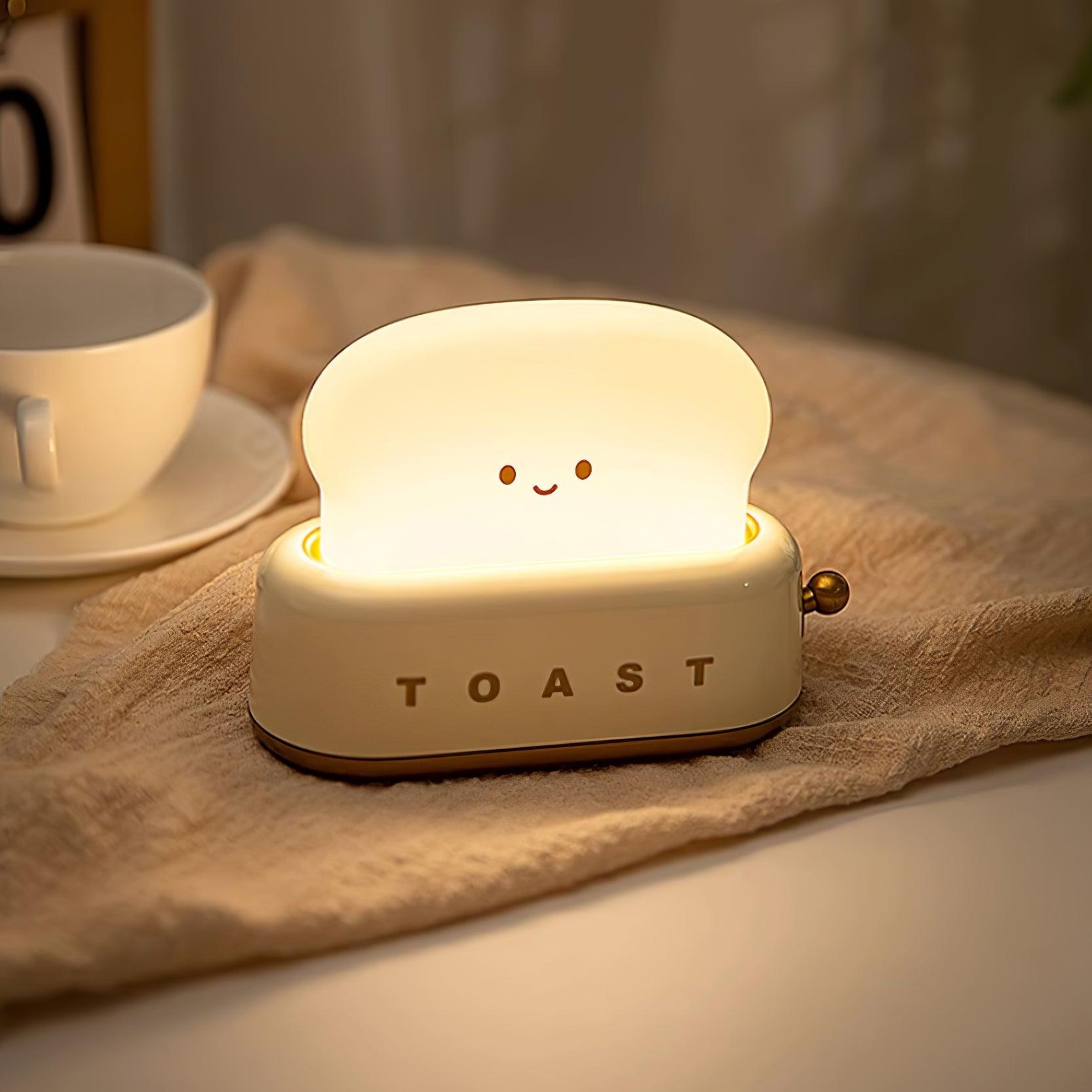 Light-up toaster-shaped night light with a smiling face on a tablecloth.
