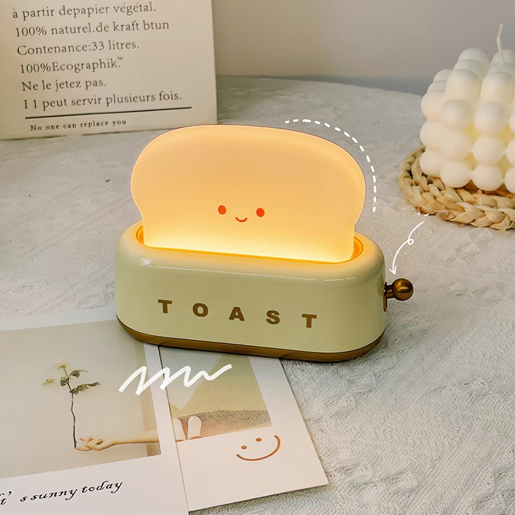 Toy toaster with a smiling face on a surface with cards and a decorative item.
