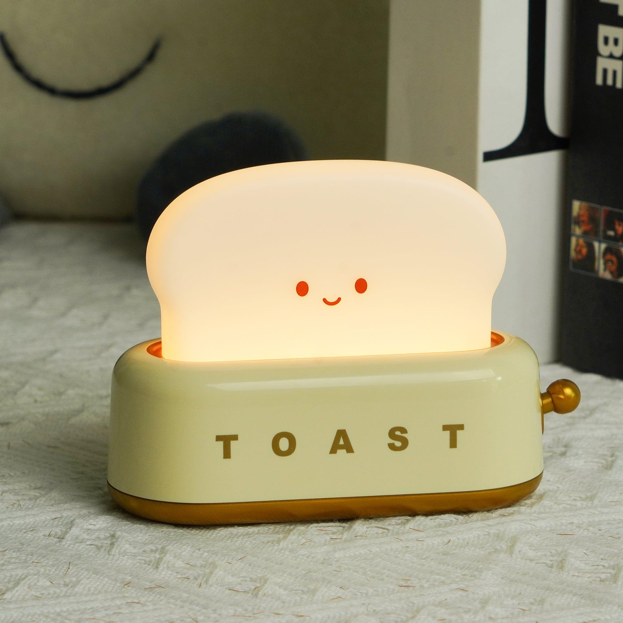 Cute toaster-shaped night light with a smiling face on a textured surface.