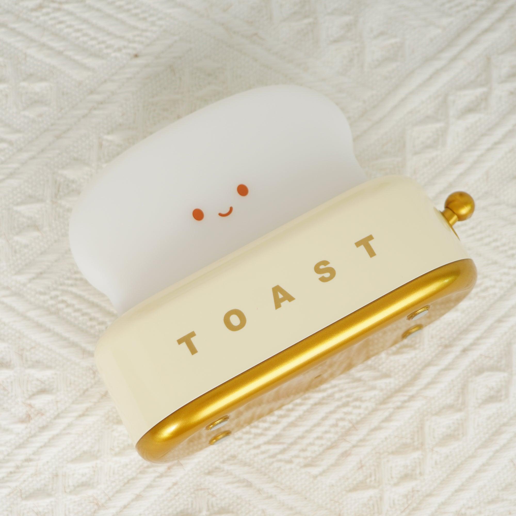 Silly toy resembling a toaster with a smiling face on a textured white background