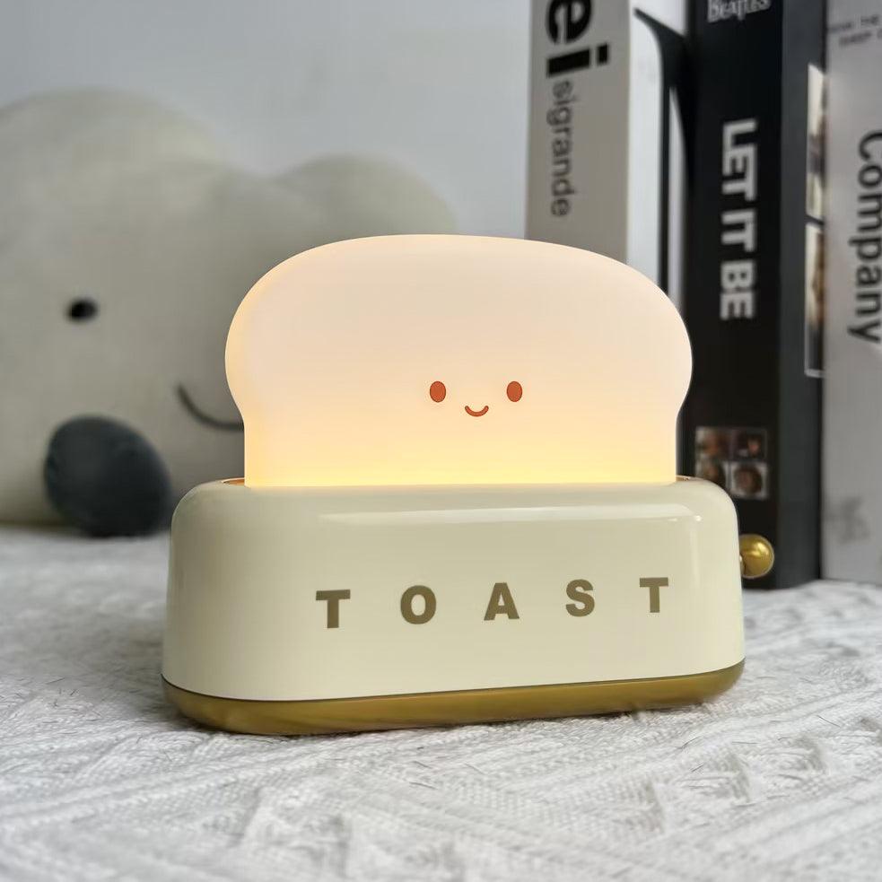 Toy toaster with a smiling face on a surface with books in the background