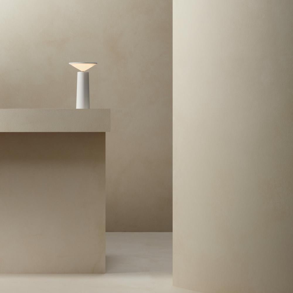 Minimalist scene with a lamp on a concrete block against a plain wall.