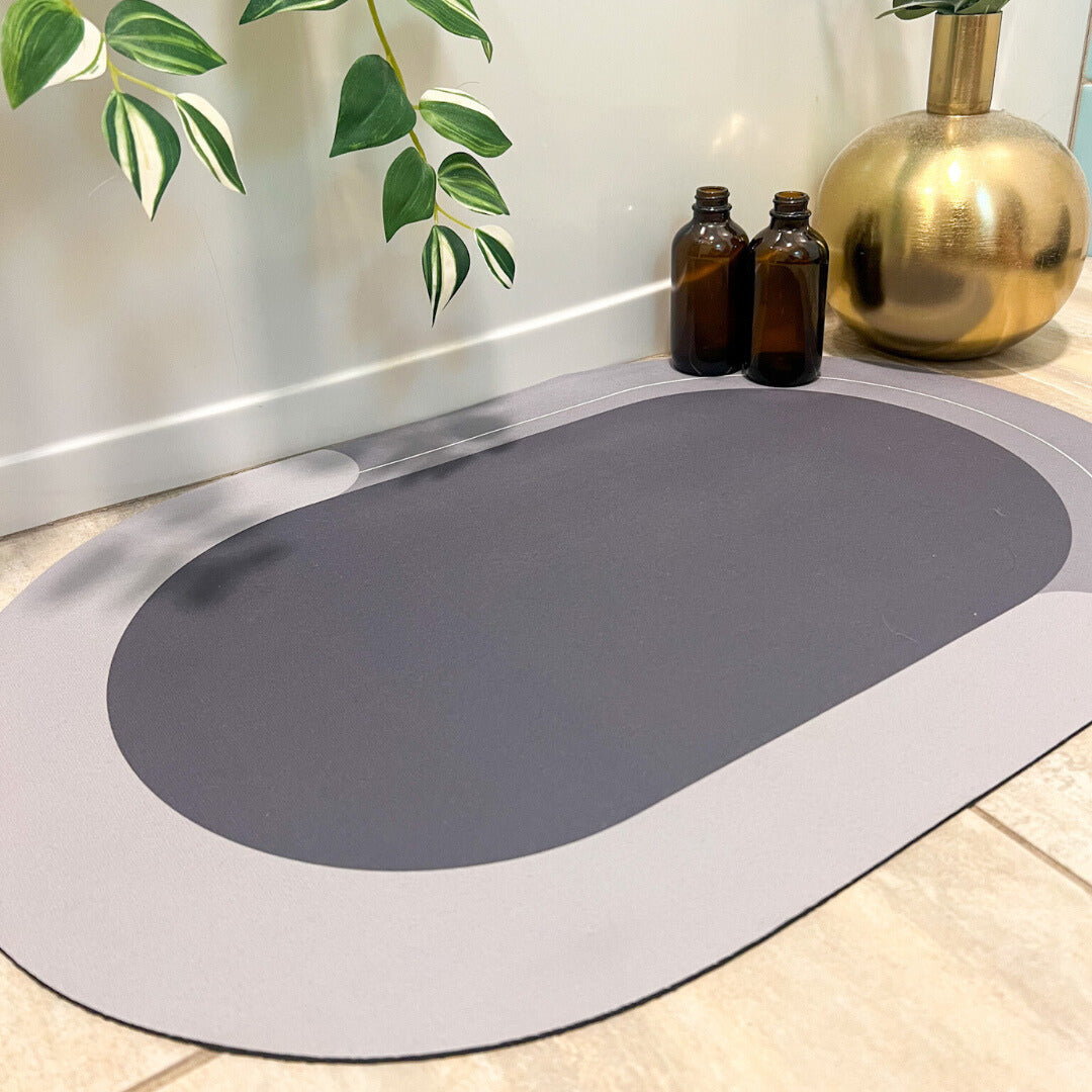 Gray oval mat on a light wooden floor with decorative items in the background