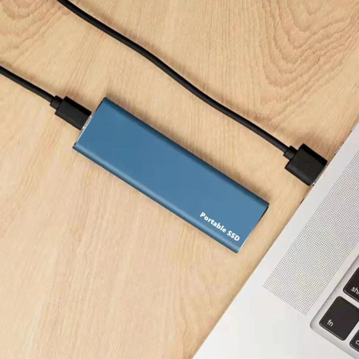 Blue portable SSD connected to a laptop on a wooden surface