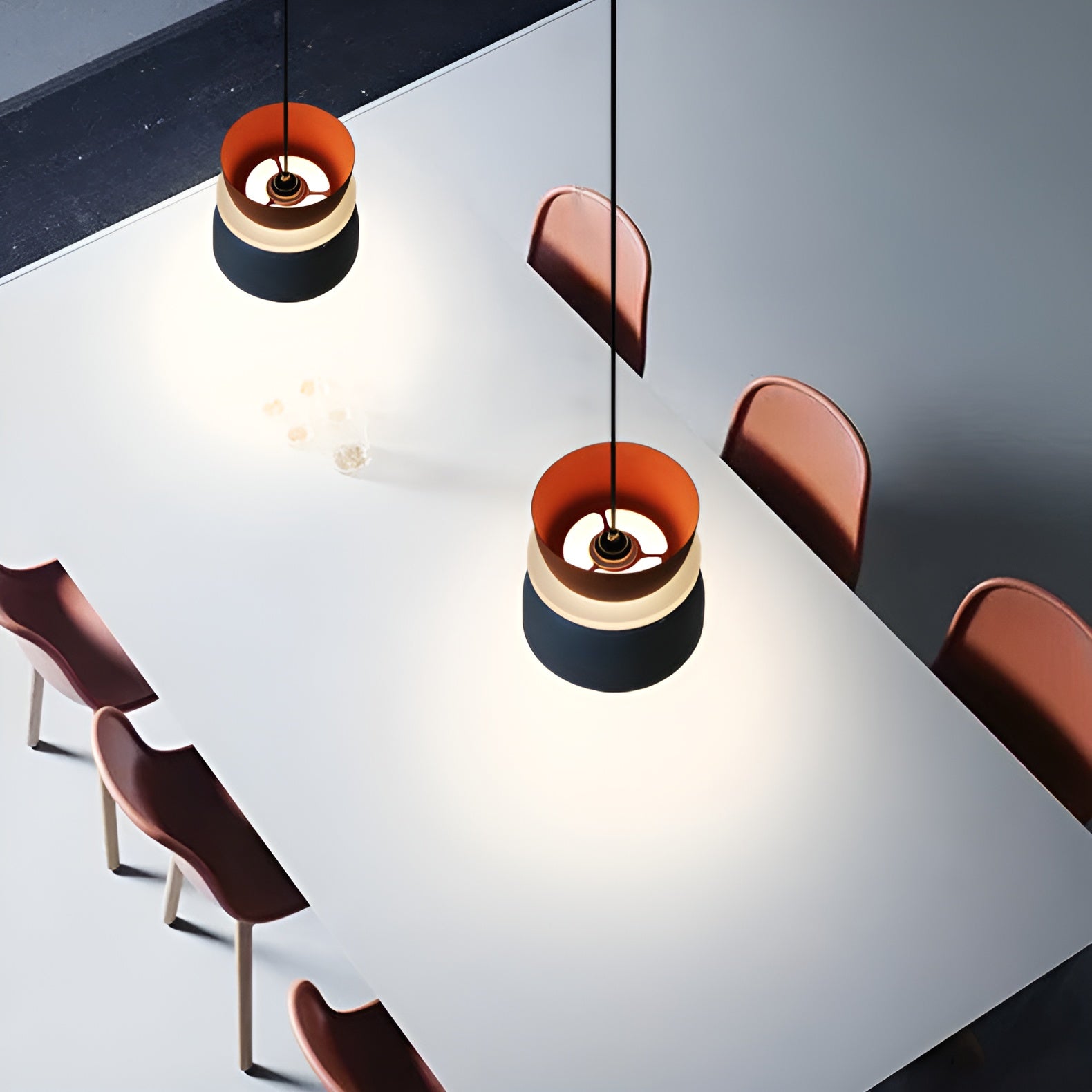 Modern pendant lights hanging above a dining table with chairs.
