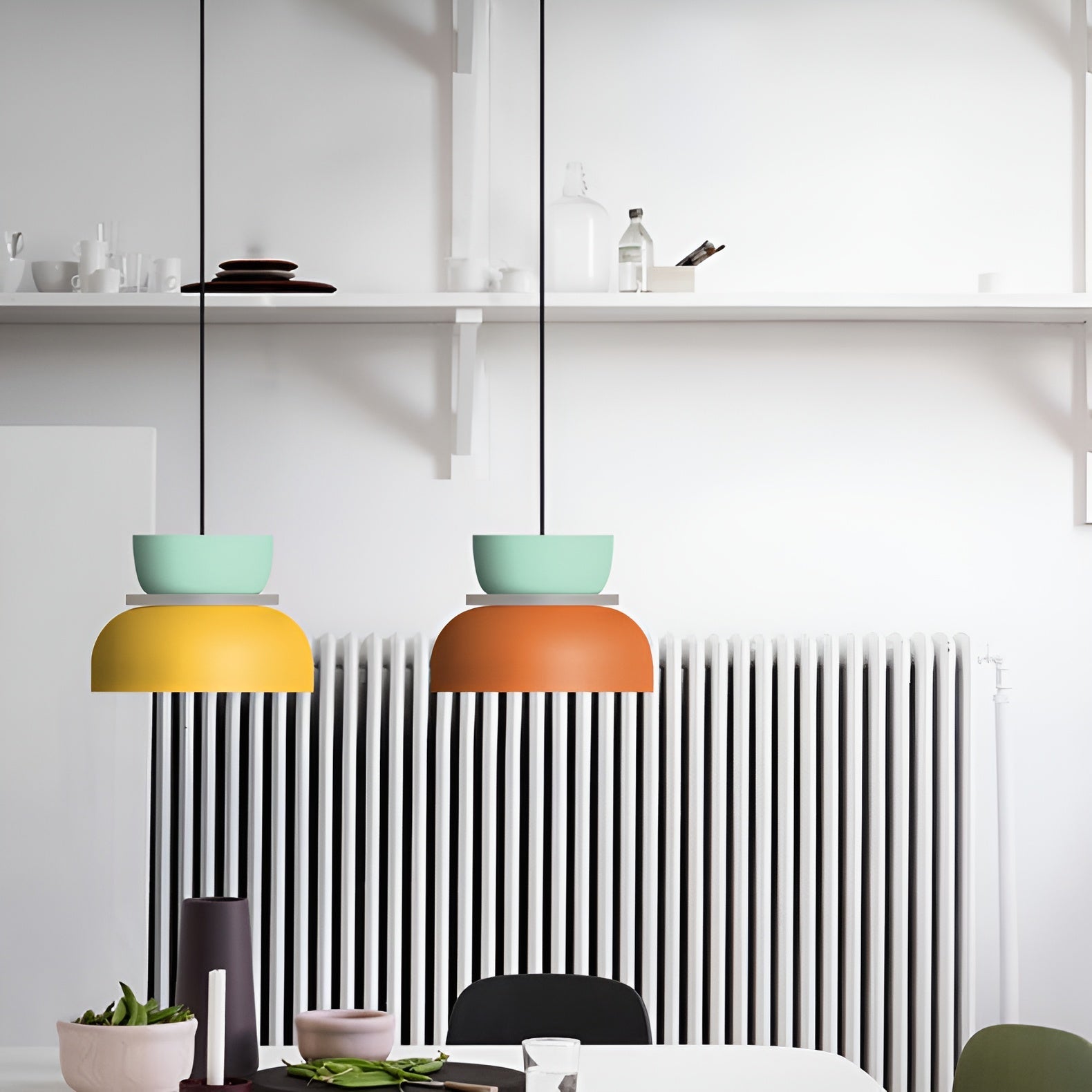 Two colorful pendant lights hanging above a dining table with a modern interior design.