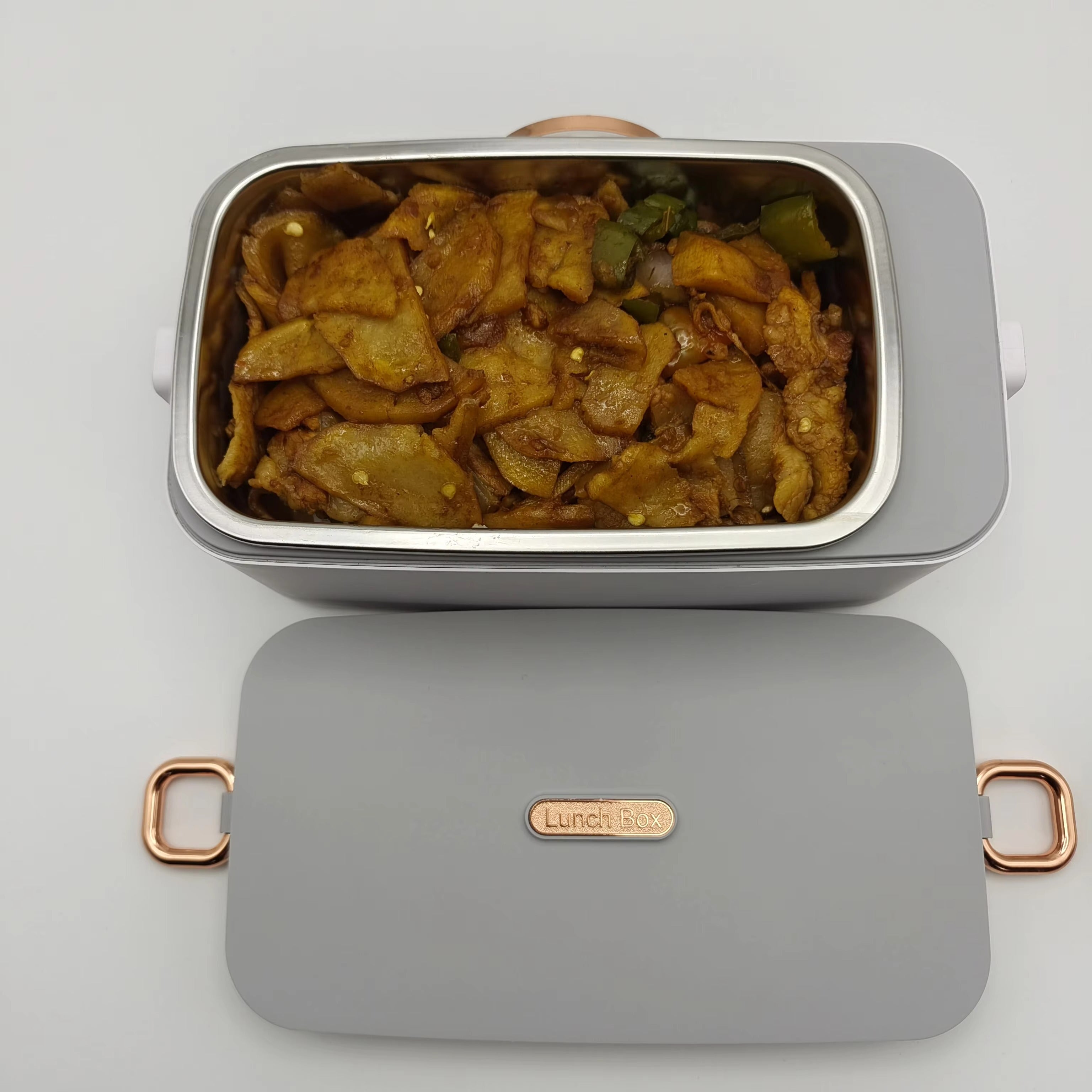 Gray lunch box with food inside on a light gray background