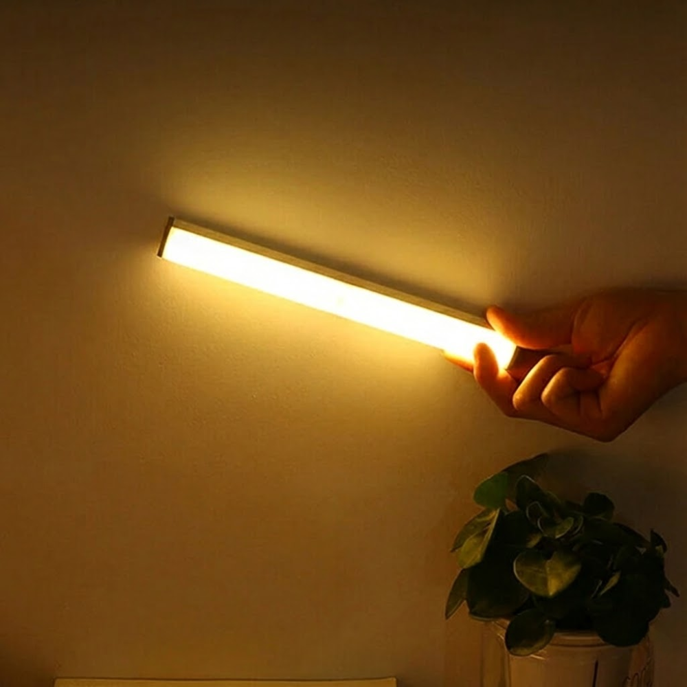 Hand holding a USB light bar against a wall with a close-up of the USB cable.