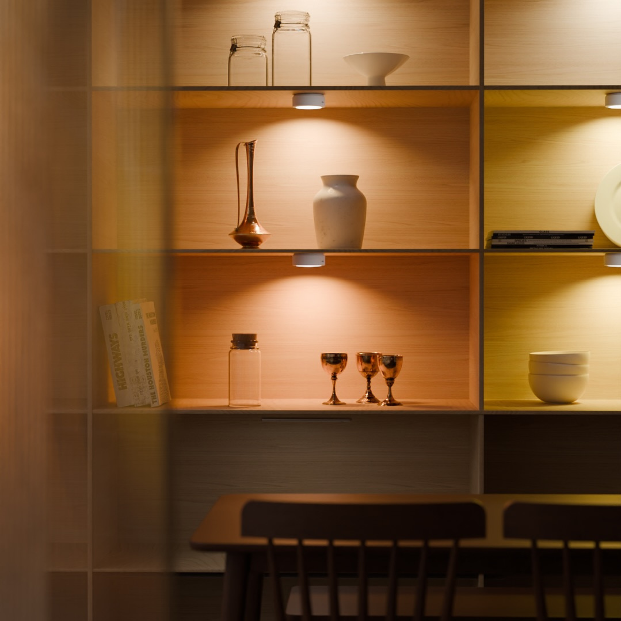 Dining area with wooden shelves displaying decorative items and a table.