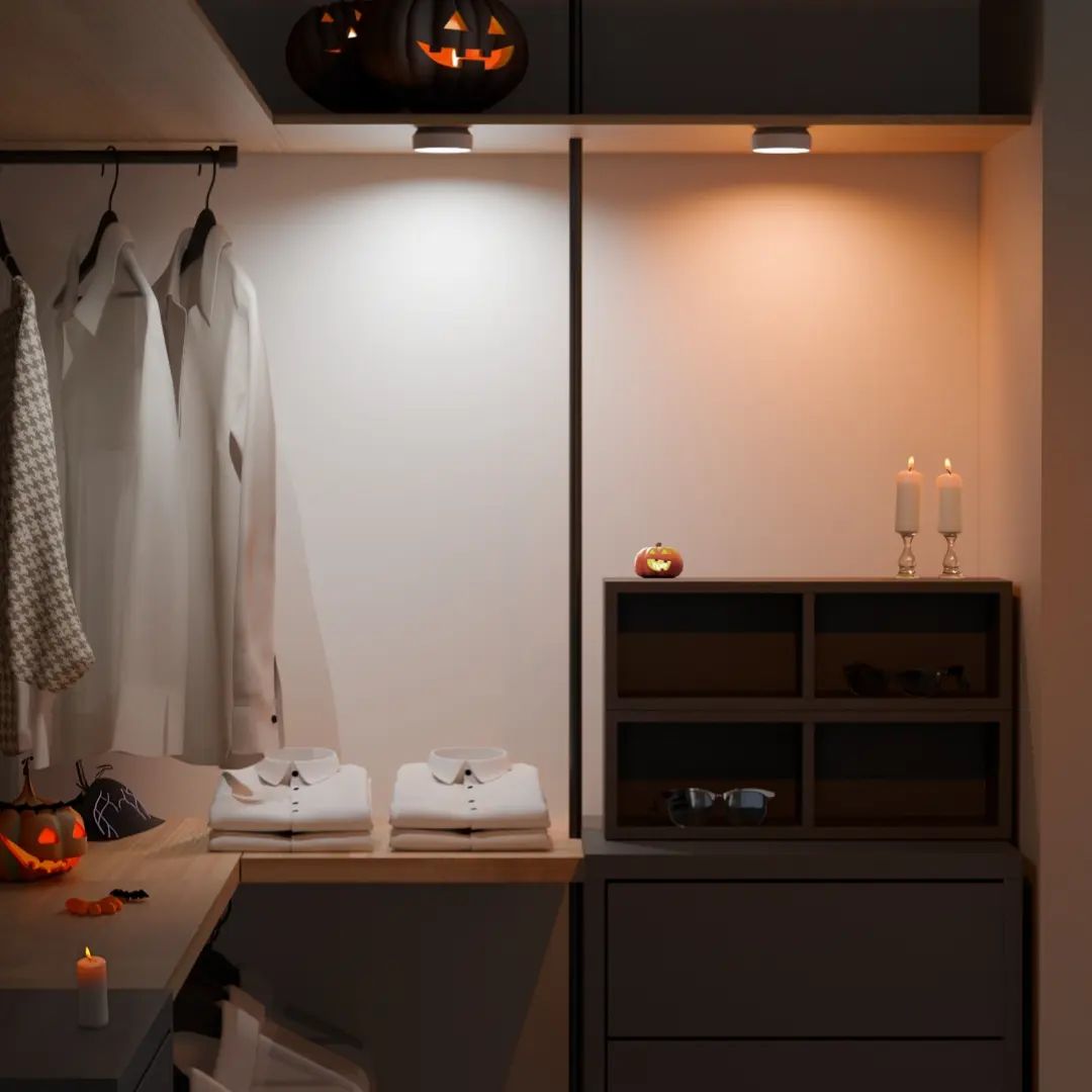 Room interior with Halloween decorations, including a pumpkin light fixture and small pumpkins on a shelf.