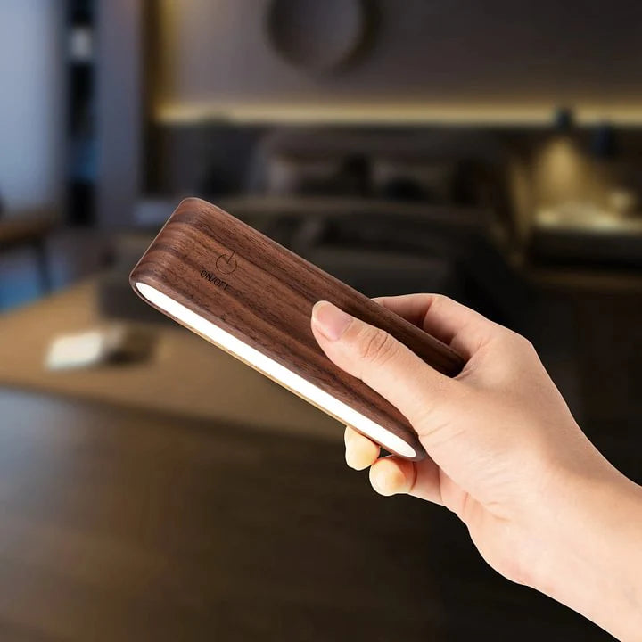 Hand holding a wooden light strip with a blurred indoor background