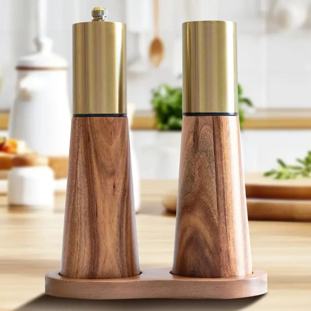 Wooden salt and pepper shakers with gold tops on a kitchen counter.