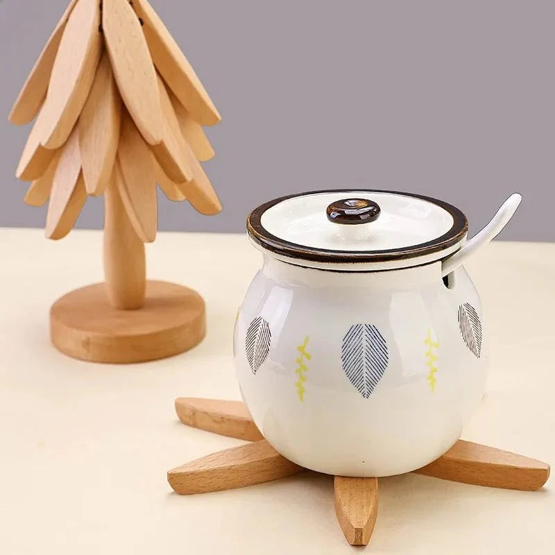 White ceramic pot with black lid and wooden base on a light surface