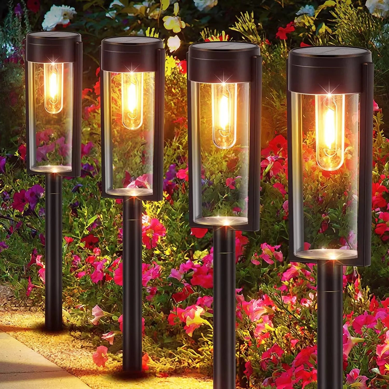 Four solar garden lights with glowing bulbs in a garden setting with flowers.