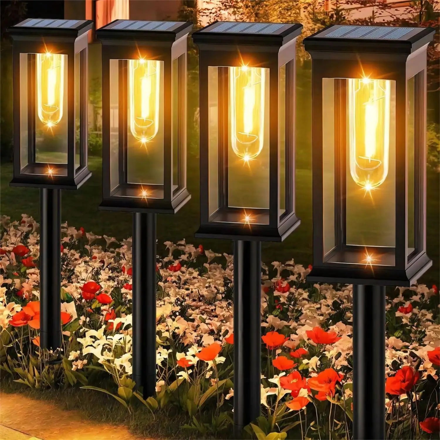 Four solar-powered garden lights on a grassy area with flowers in the background