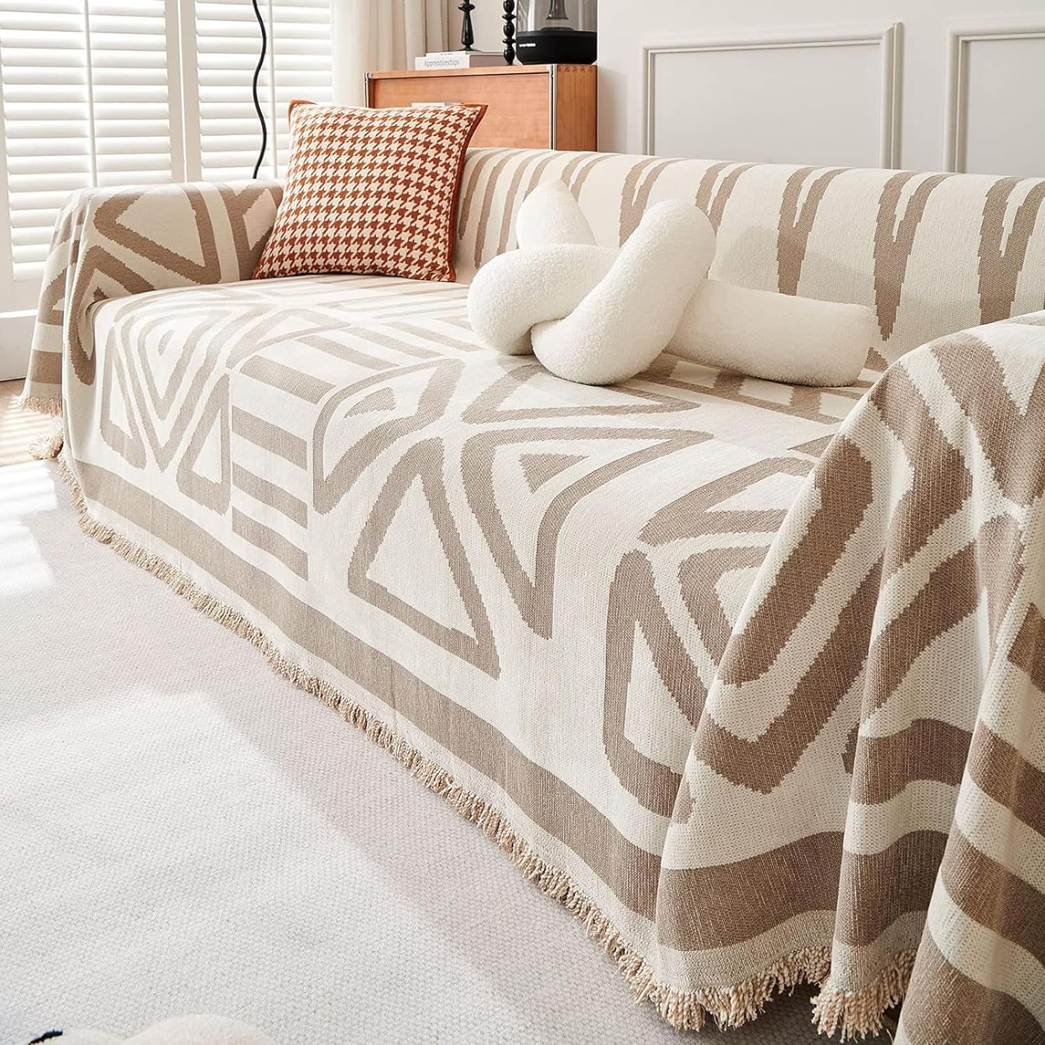 Sofa with a patterned throw blanket and cushions in a living room setting.