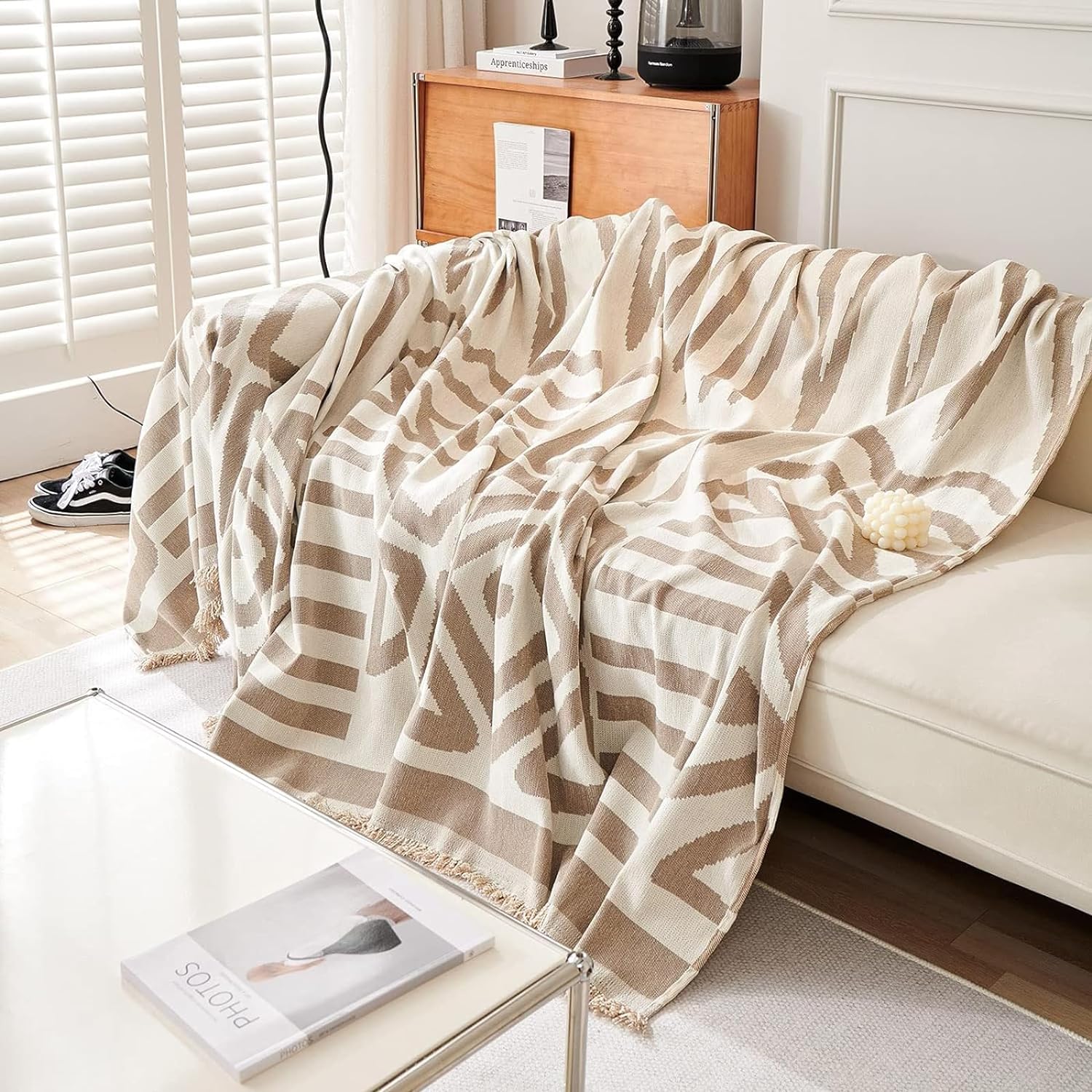 Beige and white striped blanket draped over a sofa in a living room.