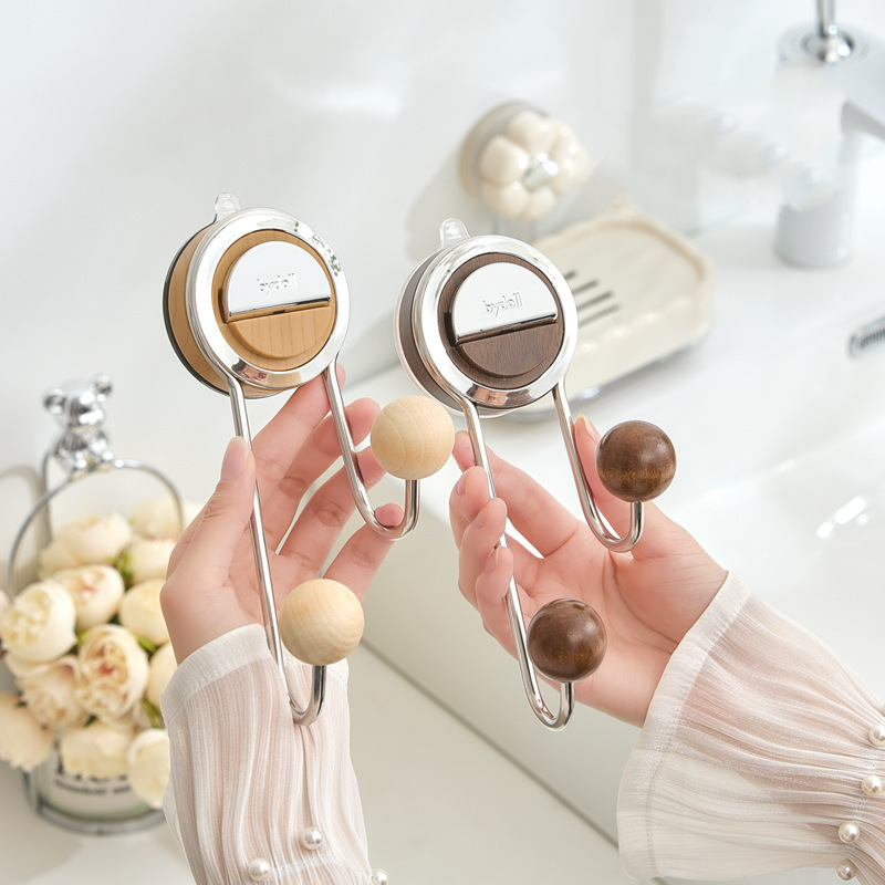 Two hands holding wooden hooks with a neutral background