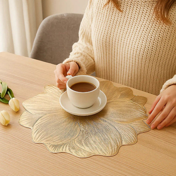 Person holding a cup of coffee on a decorative gold placemat.