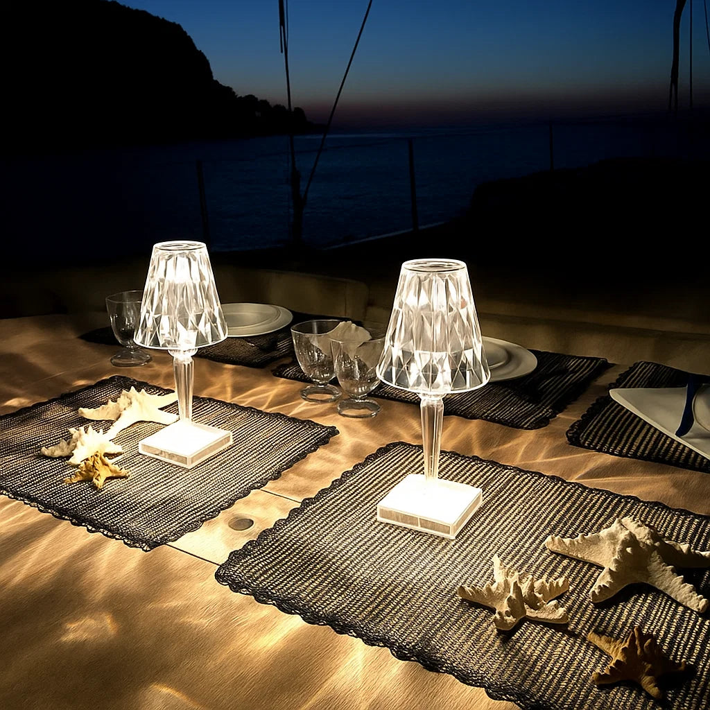 Dining table setup with crystal lamps, plates, and starfish decorations on a boat at night.