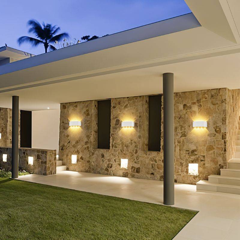 Modern outdoor setting with stone wall, columns, and decorative lights.