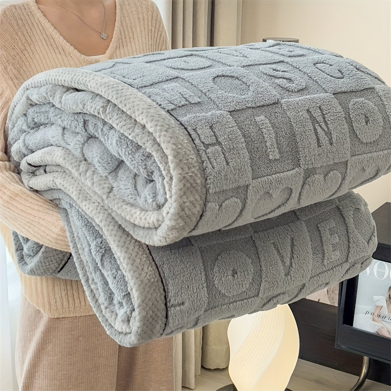 Gray textured blanket with embossed letters draped over a chair.