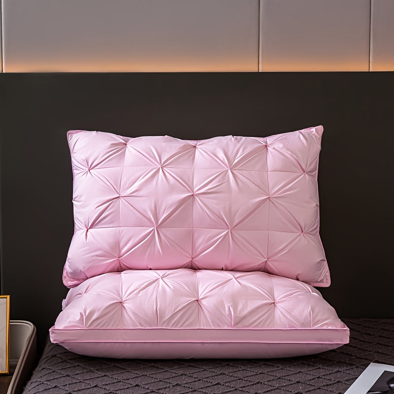 Two pink quilted pillows on a bed with a dark headboard.