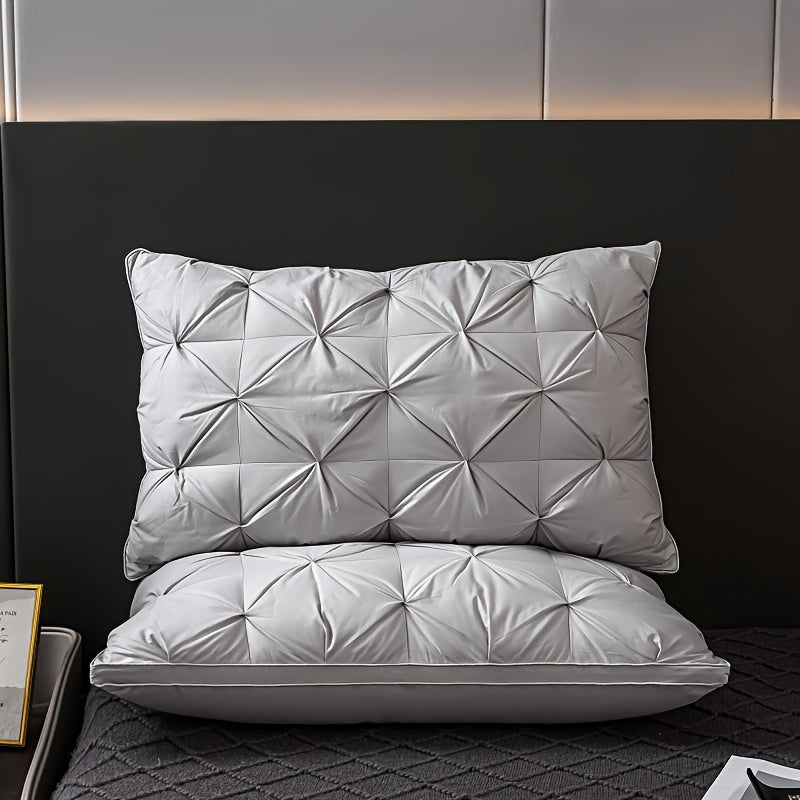 Two gray quilted pillows on a bed with a dark headboard.