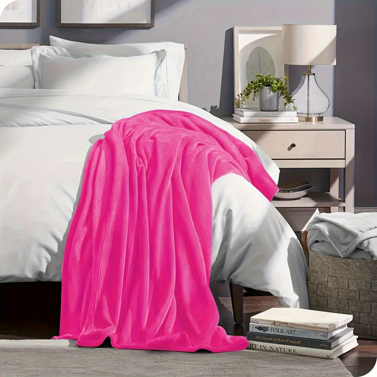 Bedroom with a pink blanket draped over a bed and a nightstand with a lamp.
