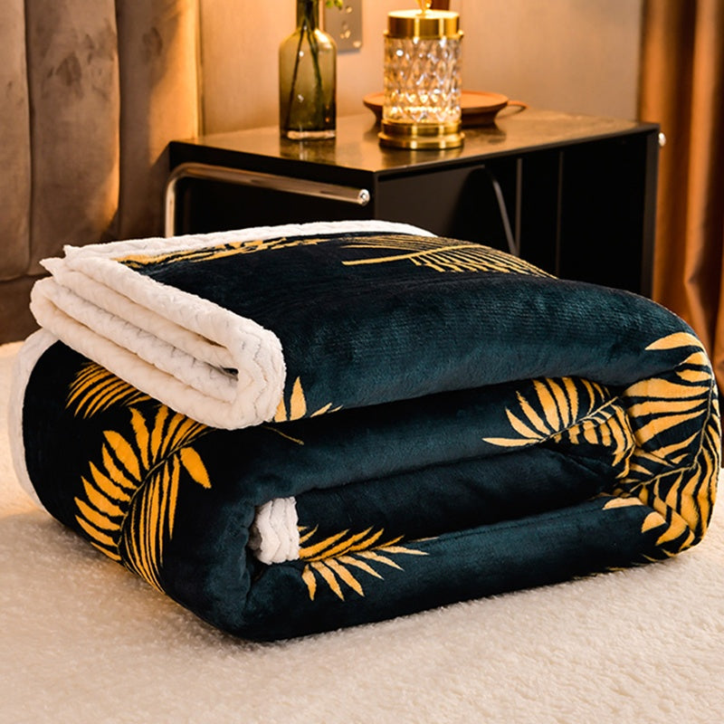 Dark blue blanket with yellow leaf pattern on a bed in a cozy room.