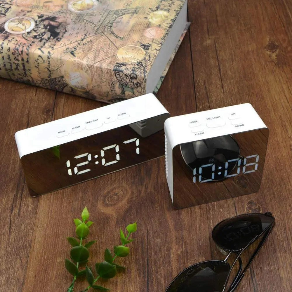 Two digital clocks on a wooden surface with a map and sunglasses in the background.