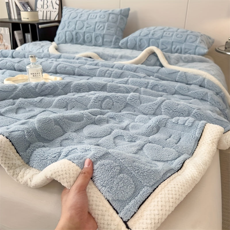 Blue textured blanket with white trim on a bed, held by a hand.