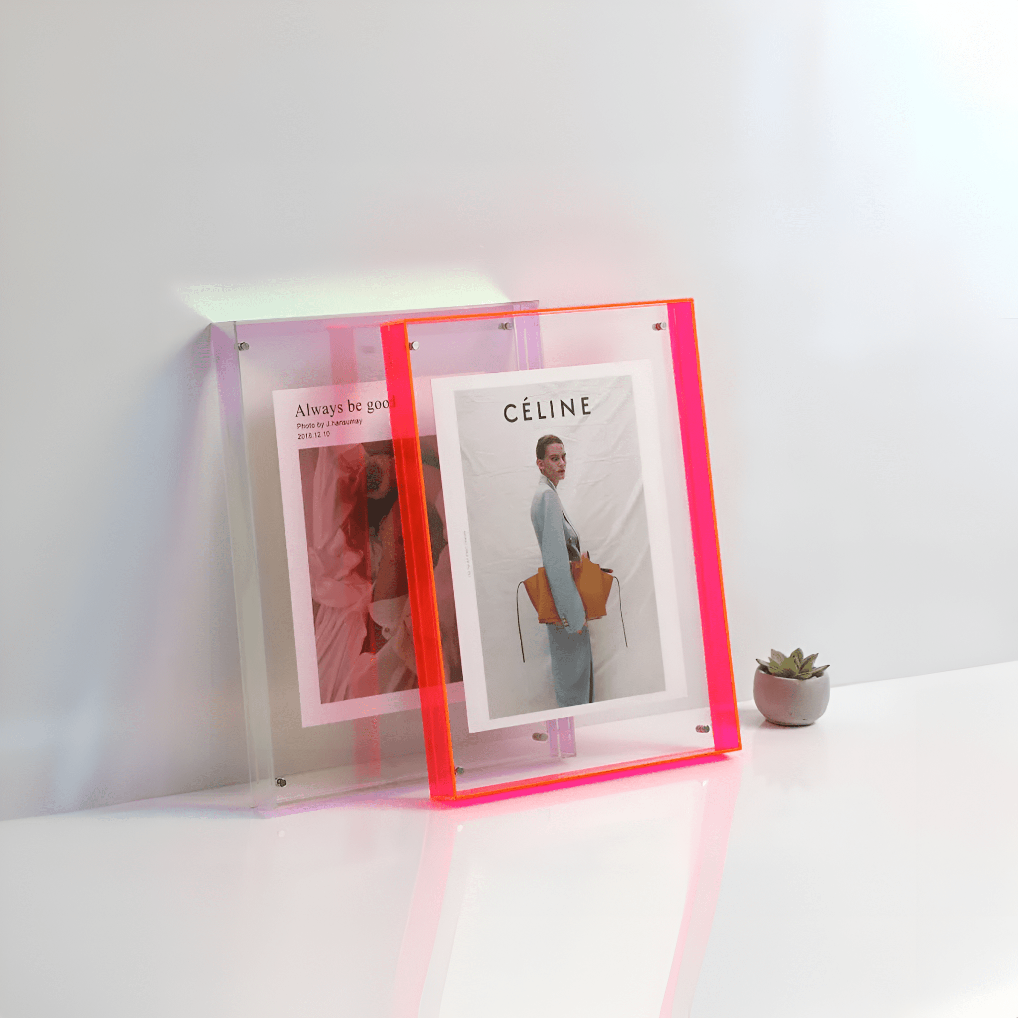 Two neon pink picture frames on a white surface with a minimal background
